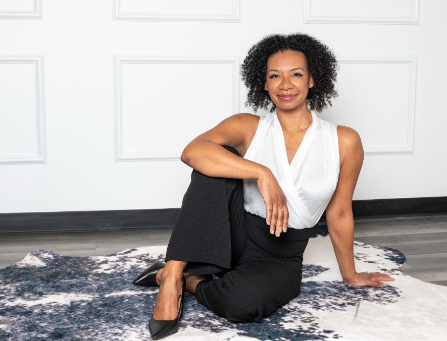 Shannon Orton seated on the floor in a white blouse and black pants